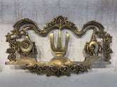 An ornate brass wall hanging displaying the U-shaped Venkateswara Namam (tilak) in the center, flanked by the Shankha (conch) and Chakra (discus) symbols, with decorative border work.